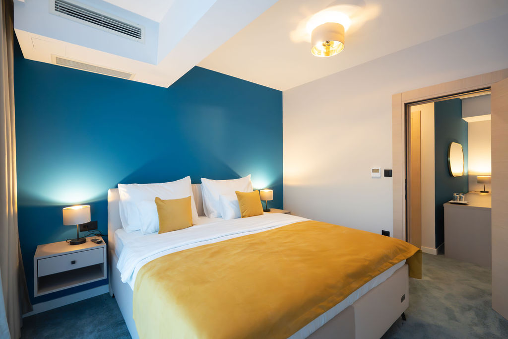 King bed with blue accent wall and golden throw